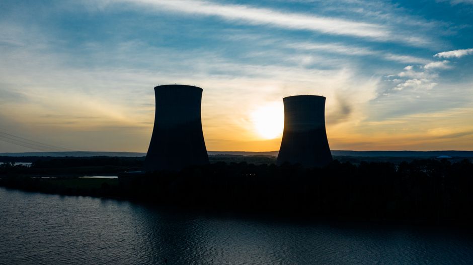 Nuclear power plant cooling towers silhouetted against a sunset sky