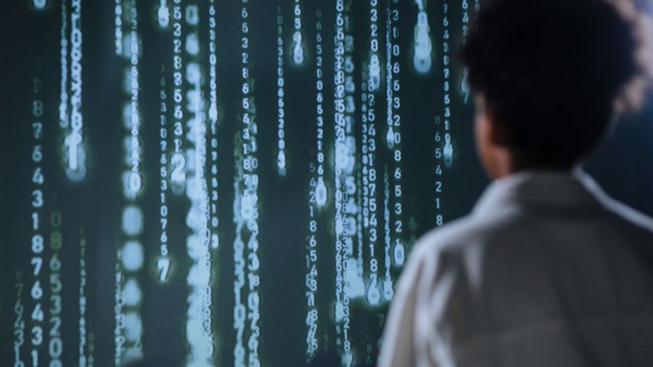 A market analyst studies data on a large screen as enterprise software and AI spending reshape the growth outlook.