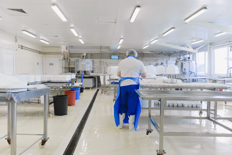 Worker in protective clothing inside a bright semiconductor-style cleanroom.