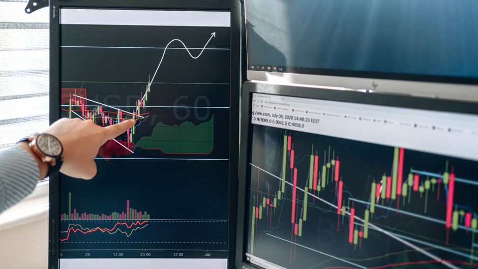 Market analyst reviewing price charts on dual monitors