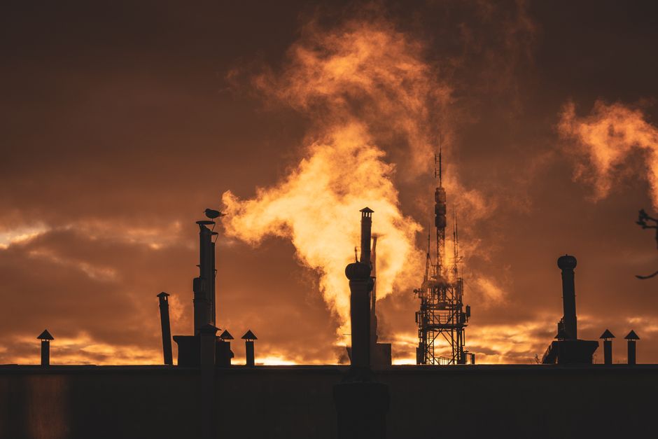 Silhouette of industrial plant smokestacks against a dramatic sunset sky, evoking the oil infrastructure at the center of this week's market shock.