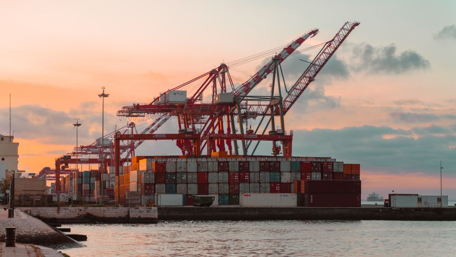 Container cranes line a commercial port as supply-chain disruption threatens longer routes and higher freight costs.