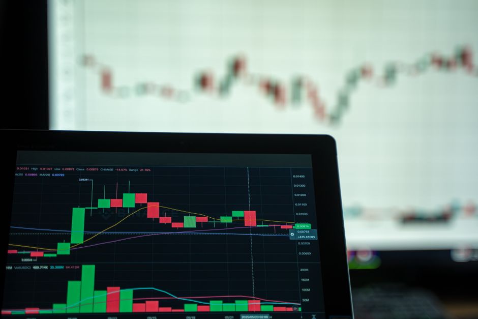 A laptop displays a detailed trading chart with candlestick price patterns and market data