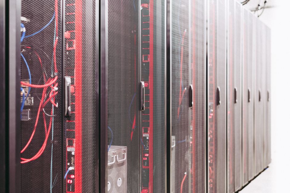 Server racks and cabling inside a modern data center, representing the infrastructure and power constraints behind the AI investment cycle.