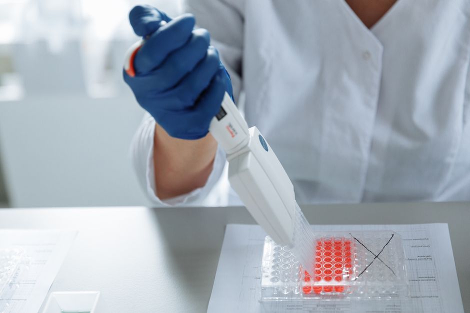 A scientist's hands using a pipette in a laboratory setting, focused on precise liquid handling.