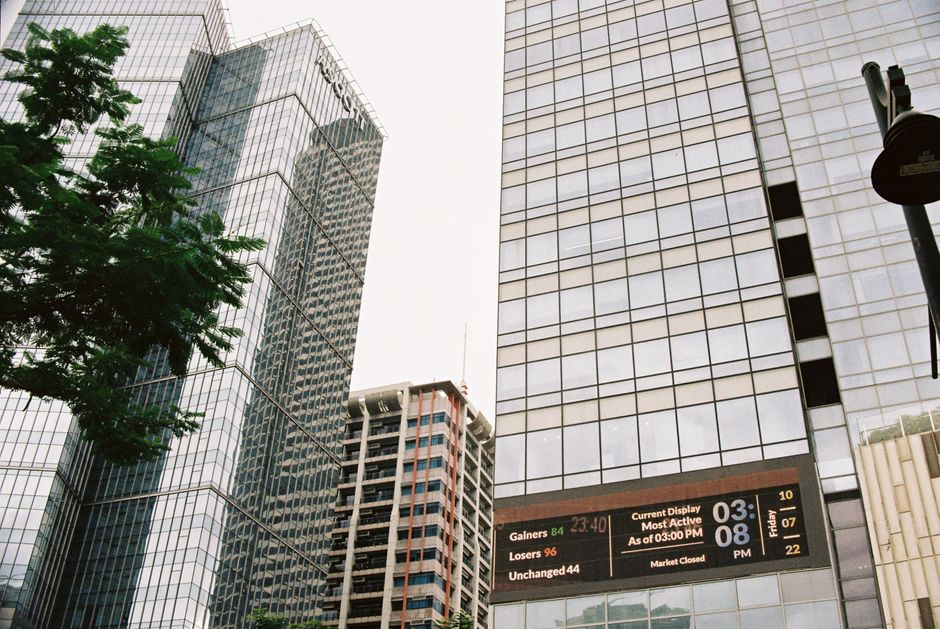 Modern skyscrapers with a digital display in a bustling urban financial district.