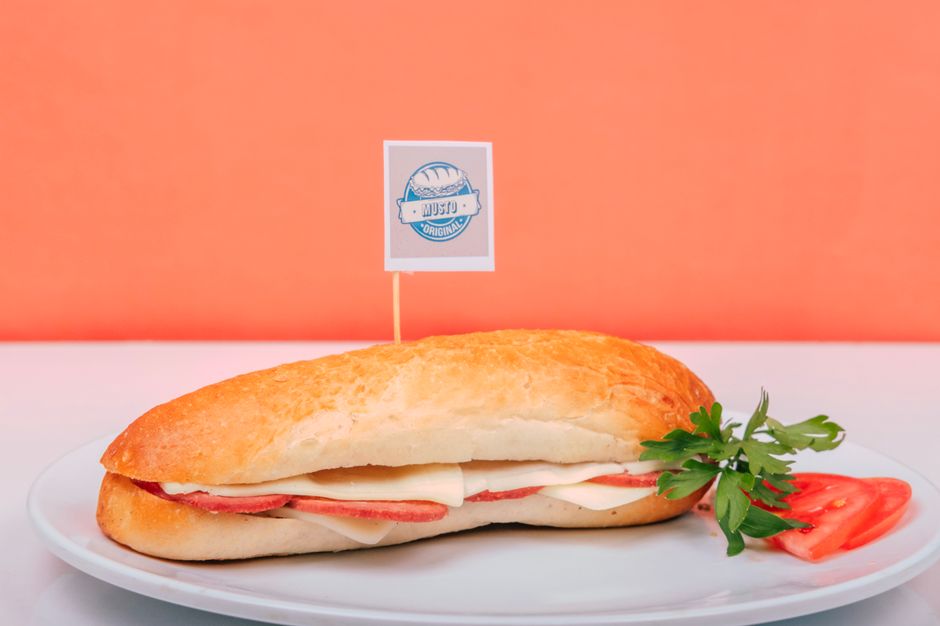 A fresh submarine sandwich with cheese, ham, and garnishes on a white plate, representing the fast-casual restaurant category.