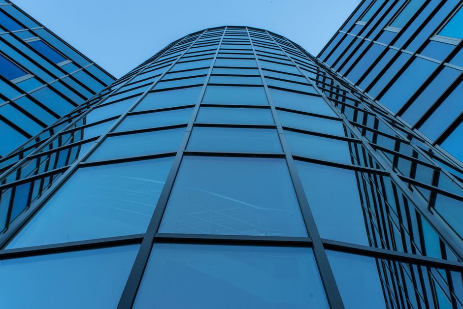 A contemporary skyscraper facade with reflective glass panels, symbolizing the corporate public listings arriving on exchanges this week.