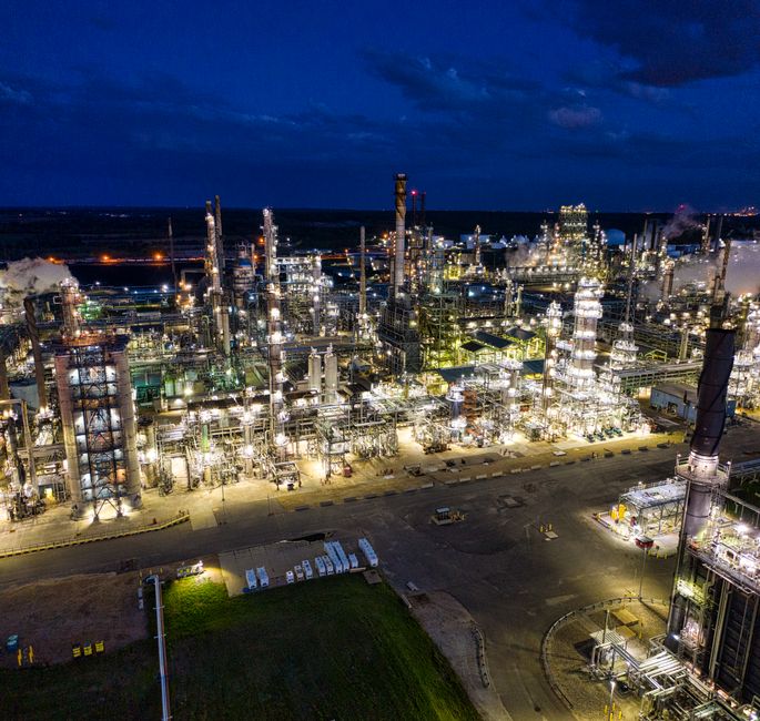 Dramatic aerial shot of an illuminated oil refinery at night.