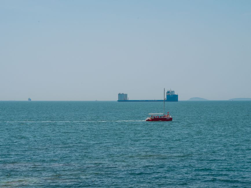 Cargo ships sailing in open sea with distant vessels on the horizon under a hazy sky