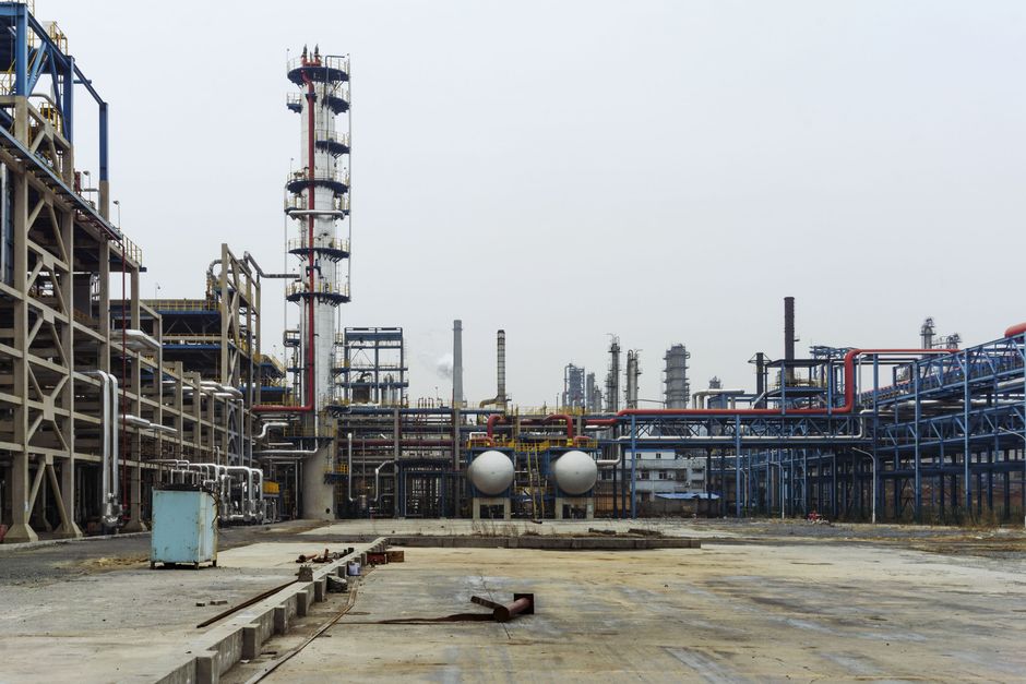 Industrial petrochemical refinery with pipelines and steel structures, representing the energy infrastructure at risk as Hormuz tanker traffic collapses.