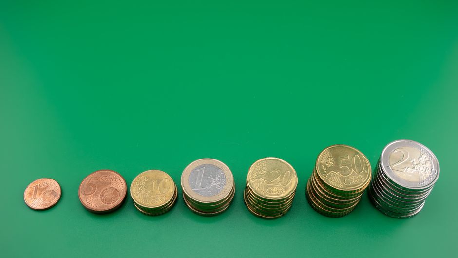 Coins stacked incrementally on a green background, representing capital growth.