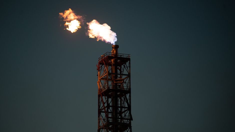 Industrial refinery flare burning against a dark sky