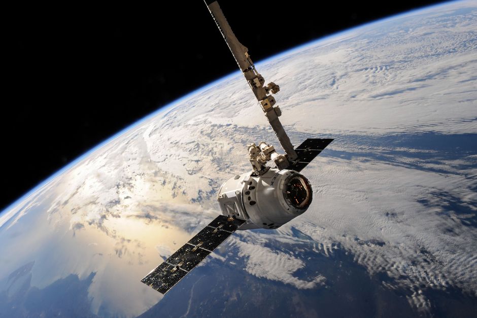 A satellite orbiting above Earth with dramatic cloud formations, representing the space infrastructure sector SpaceX leads.