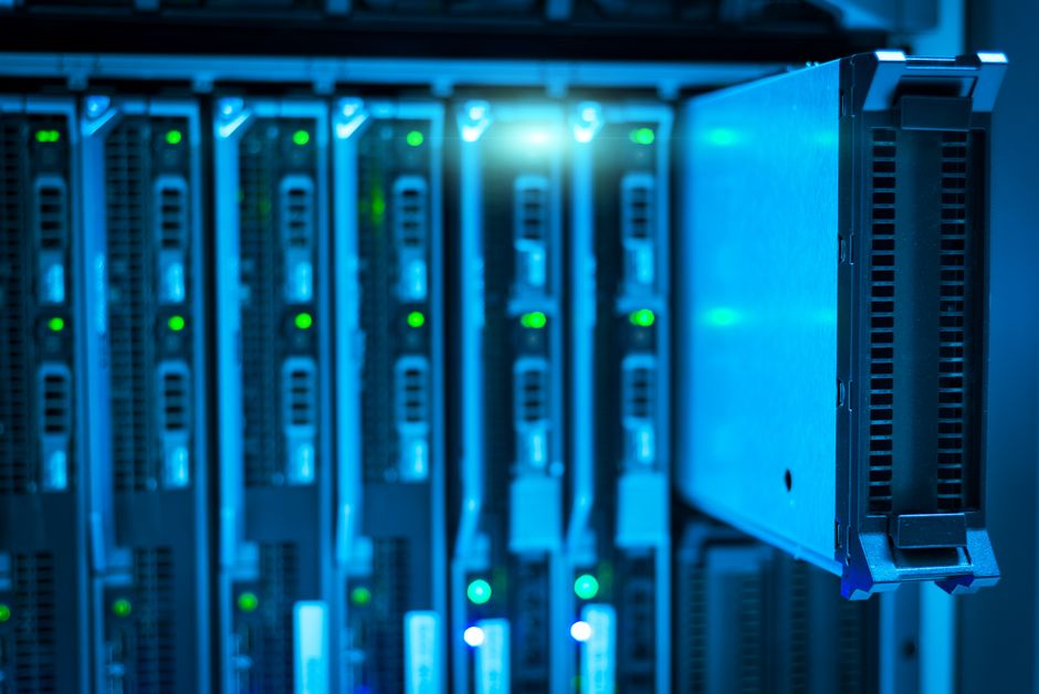 Close-up of a server rack with blue LED lighting in a data center, representing the AI infrastructure buildout now under market scrutiny.