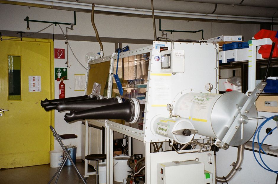 Industrial laboratory equipment in a semiconductor manufacturing facility, featuring a sealed glove box workstation used in clean-room fabrication processes.
