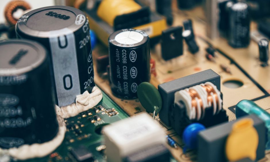 Macro close-up of electronic capacitors and resistors on a dark green circuit board showing fine component details
