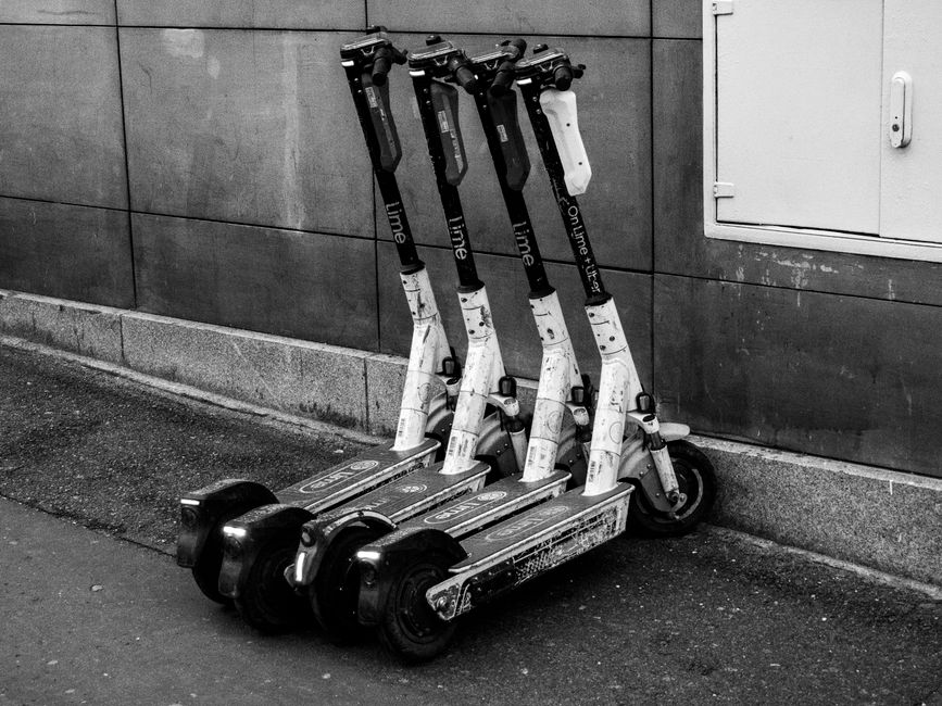 A row of shared electric scooters parked along a building wall