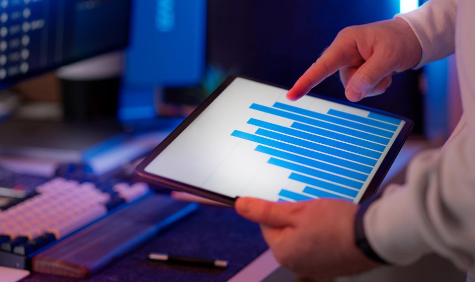 A professional reviews operating data on a tablet in an office.