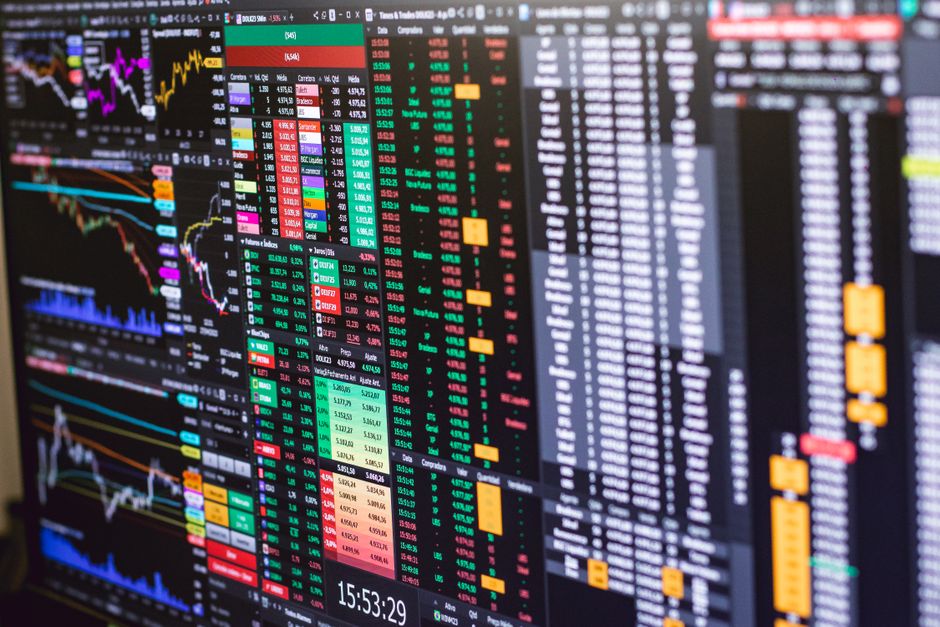 Financial trading screens displaying colorful market data and charts