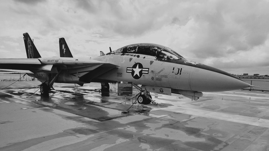 Military fighter jet on a wet tarmac under cloudy skies
