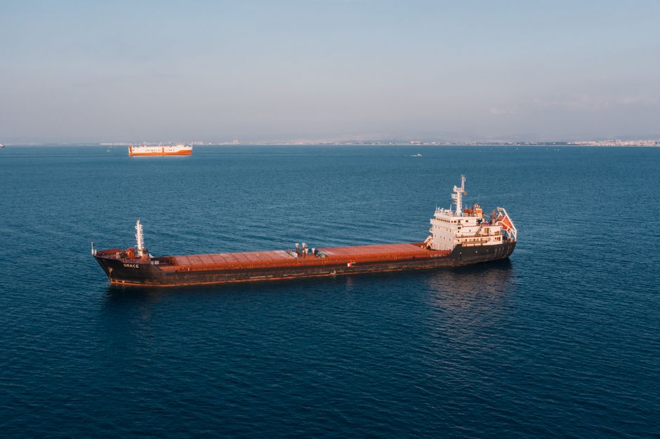 Aerial view of a cargo ship sailing in the open sea under clear skies.