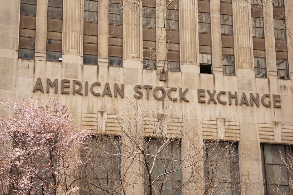 Facade of the American Stock Exchange Building in New York City with blooming trees in spring.