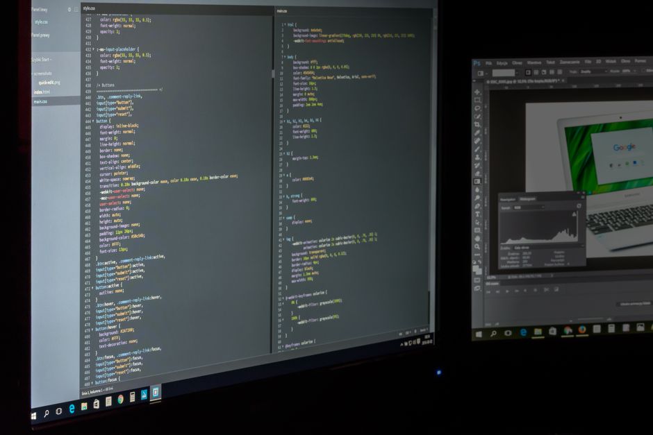 A developer's dual-screen workstation displays programming code and monitoring dashboards side by side.