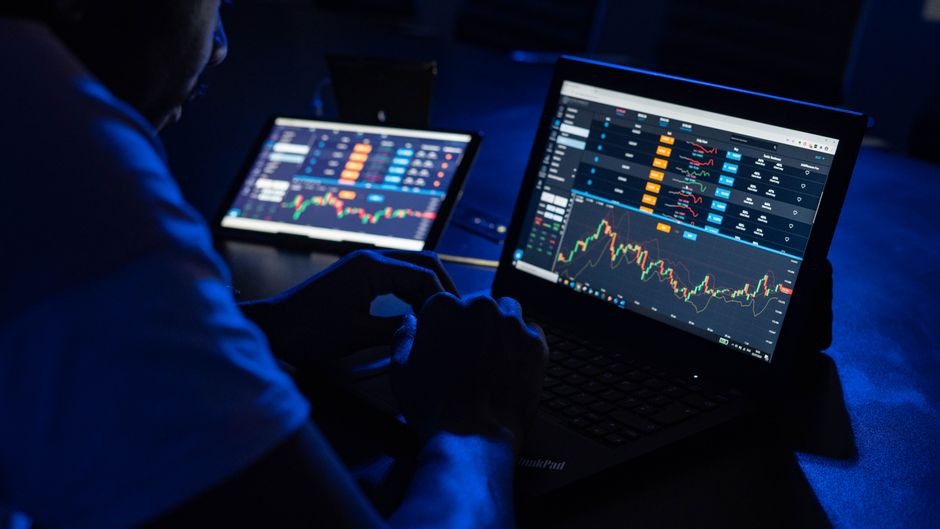 A market monitor displays stock graphs representing IPO aftermarket liquidity and order-book depth.