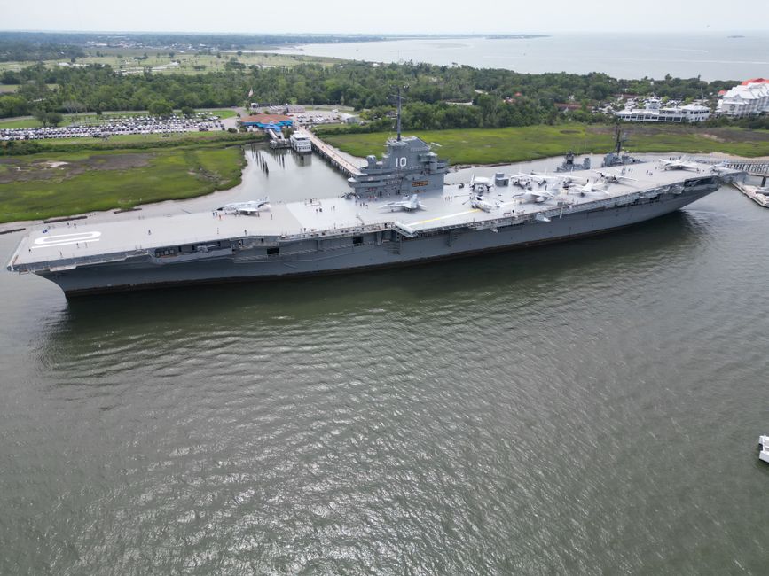 Aerial view of a navy aircraft carrier docked in a harbor.