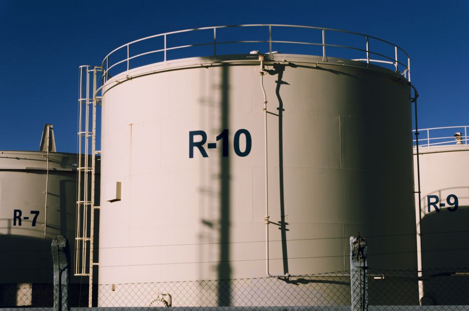 Industrial storage tanks representing energy infrastructure and the commodity channel influencing markets.