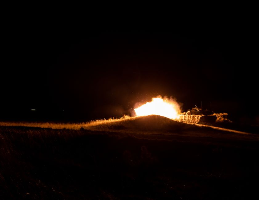 A powerful fireball eruption during nighttime military activity creates a dramatic scene