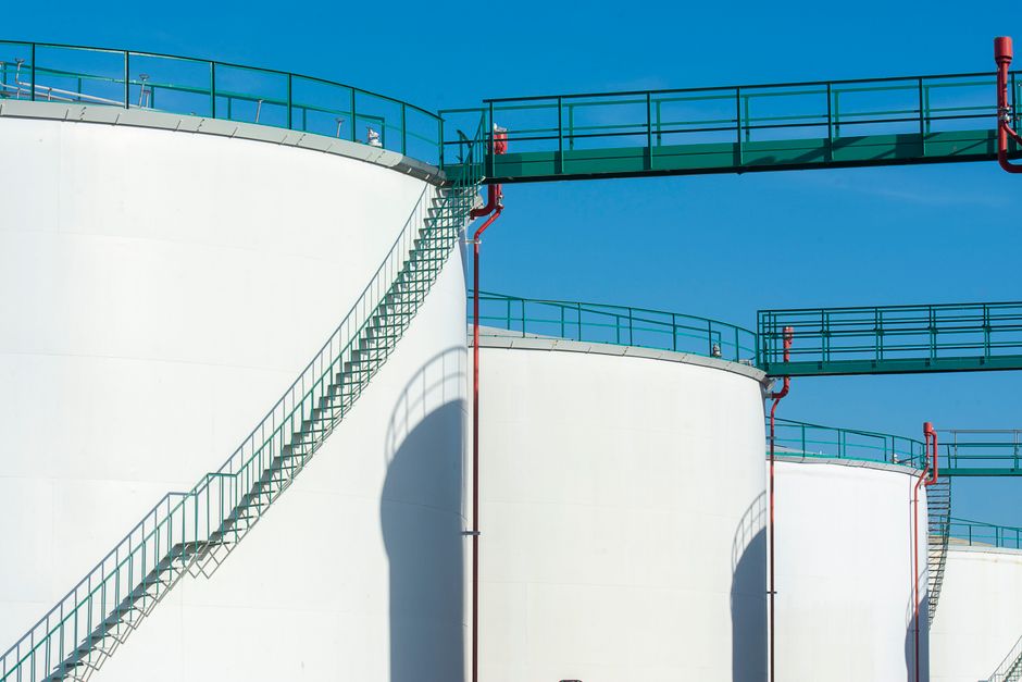 Large industrial storage tanks with a walkway under a clear sky, representing the energy infrastructure now exposed to Houthi attack at Yanbu.