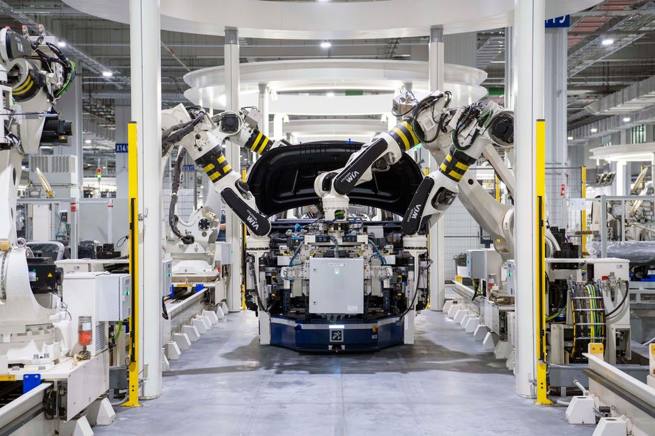 Robotic arms assembling vehicles on a factory production line