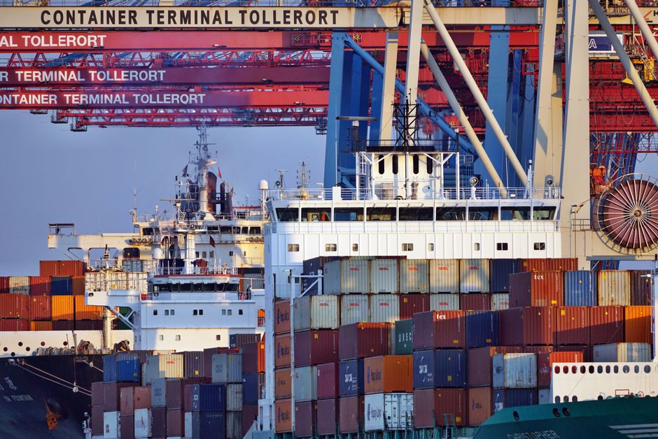 Container ships docked at a port terminal at sunset.
