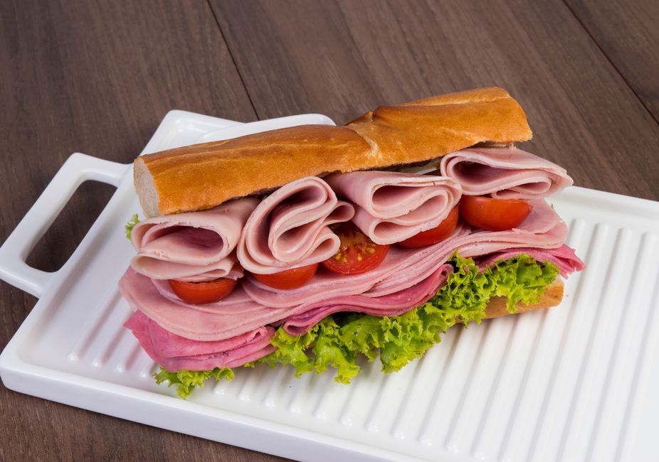 Stacked ham and salami sandwich with lettuce and tomatoes on a tray