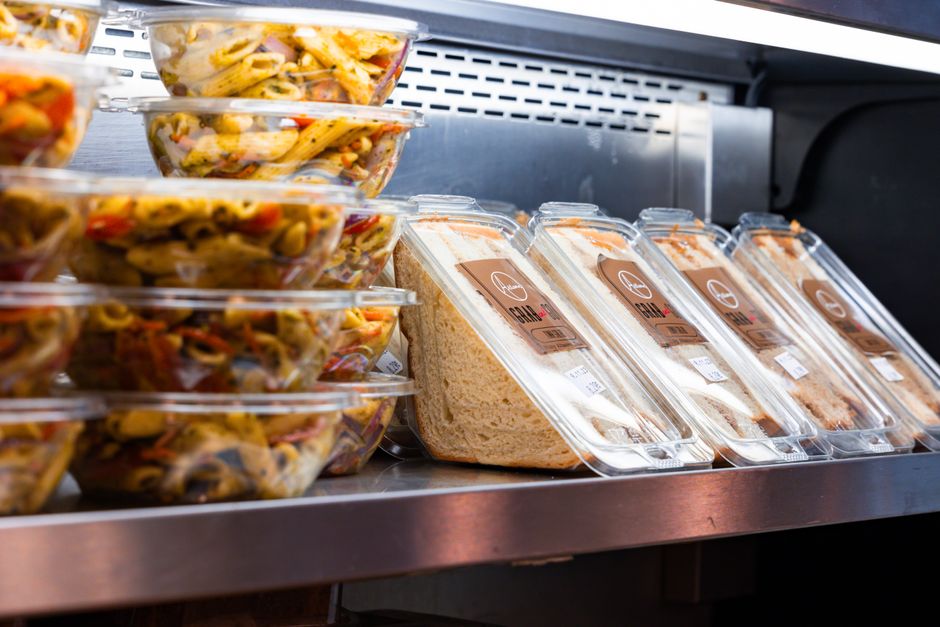 Deli sandwiches and prepared foods displayed in a store refrigerator