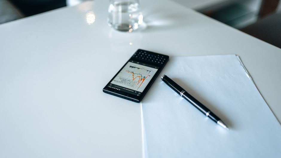 Smartphone displaying a stock market graph on a white desk