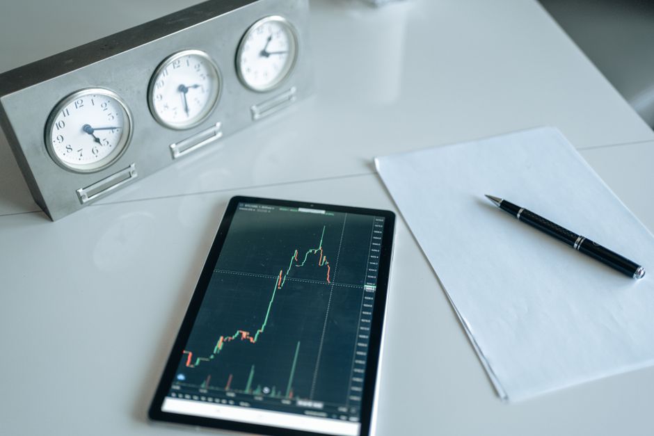 Trading desk with tablet showing market data alongside analog clocks