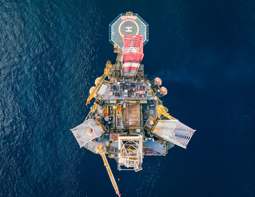 Offshore oil platform with helipad surrounded by deep blue ocean, symbolizing the Gulf energy infrastructure caught between war disruption and post-ceasefire recovery.