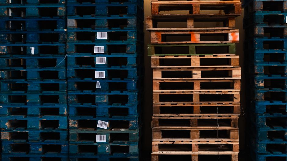 Rows of warehouse pallets represent tariff exposure and logistics costs in home retail supply chains