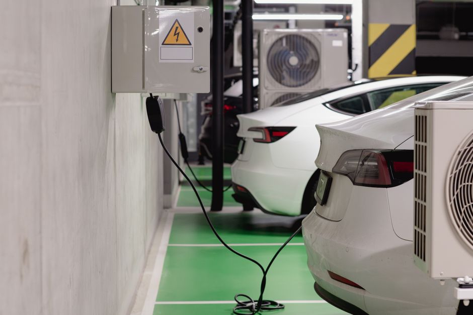 Electric vehicles charging at stations in a modern underground parking garage.