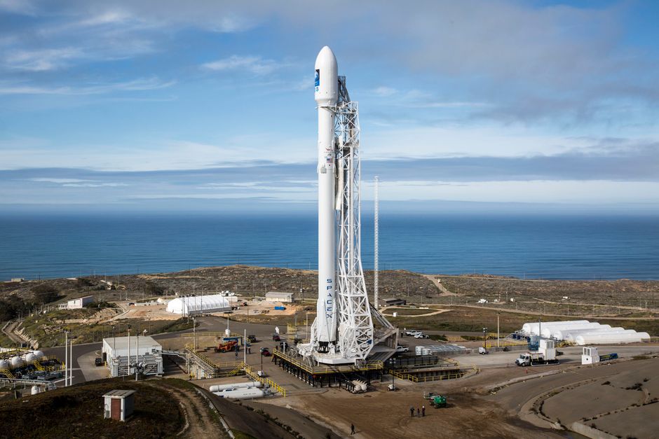 SpaceX rocket standing on a launchpad overlooking the ocean under a clear sky
