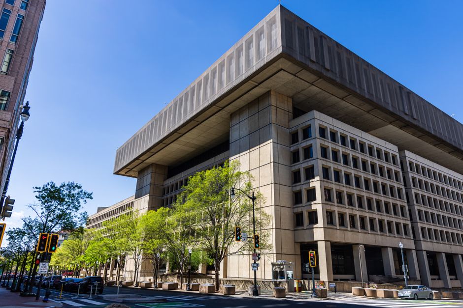 Modernist government building with a distinct overhang, photographed on a sunny day with clear blue skies.