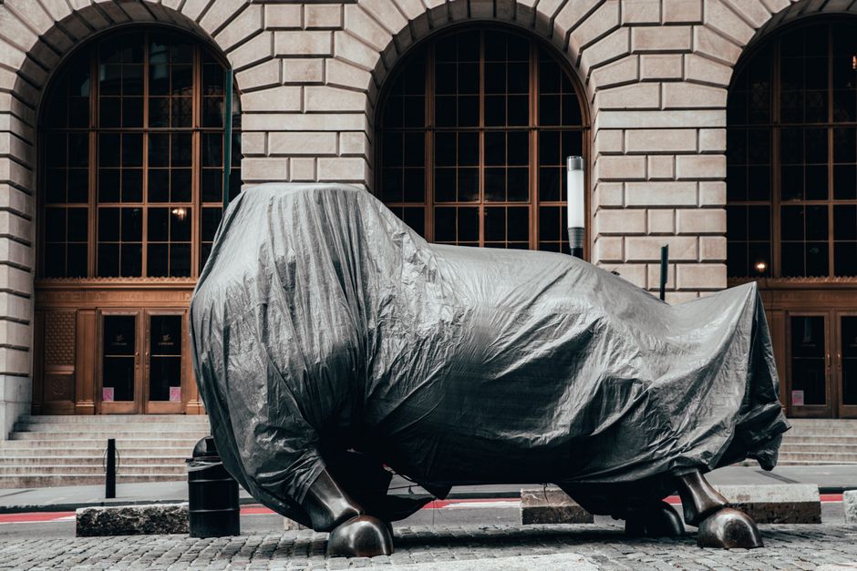 Covered statue of Charging Bull on Wall Street, New York City, symbolizing market volatility.