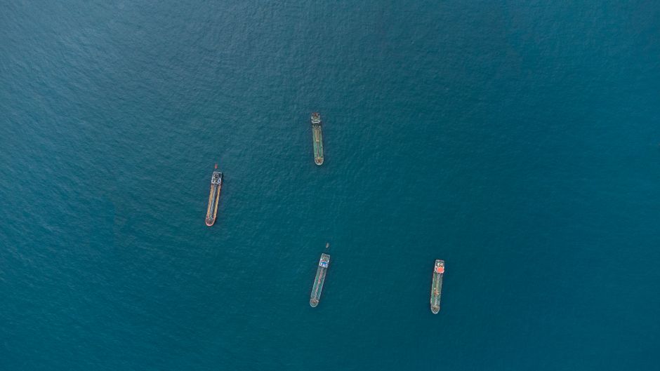 Top-down aerial view of cargo ships sailing on open ocean.