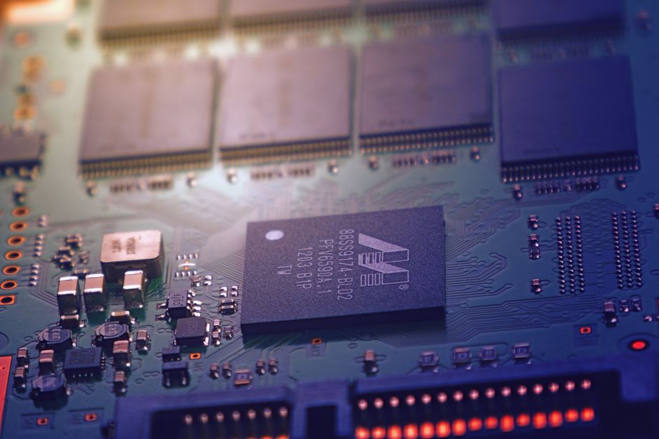 Close-up of a green electronic circuit board with microchips and intricate wiring, representing semiconductor hardware.