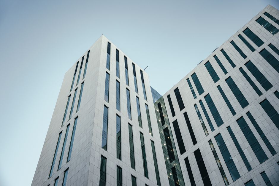 Low-angle view of a contemporary multistory building with geometric glass windows against a clear blue sky