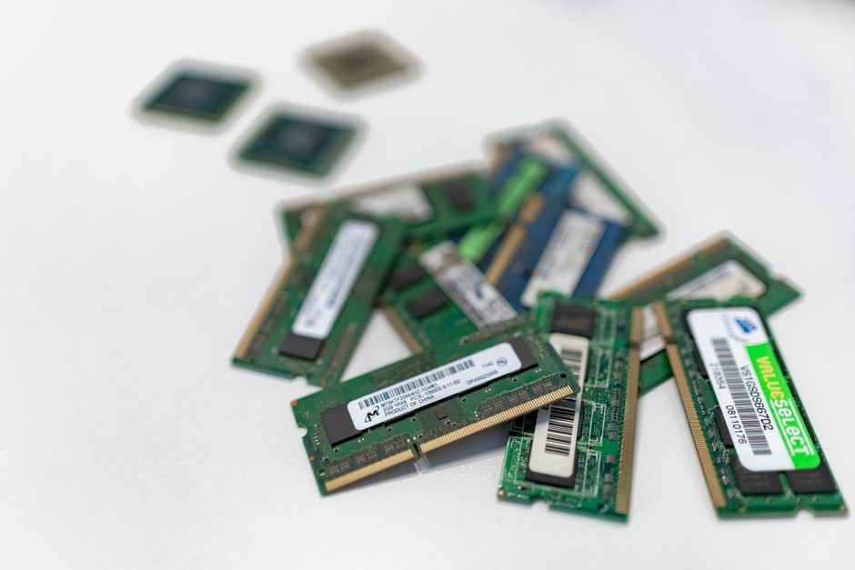 Assorted RAM memory modules arranged on a white surface, showing circuit components and green board material.