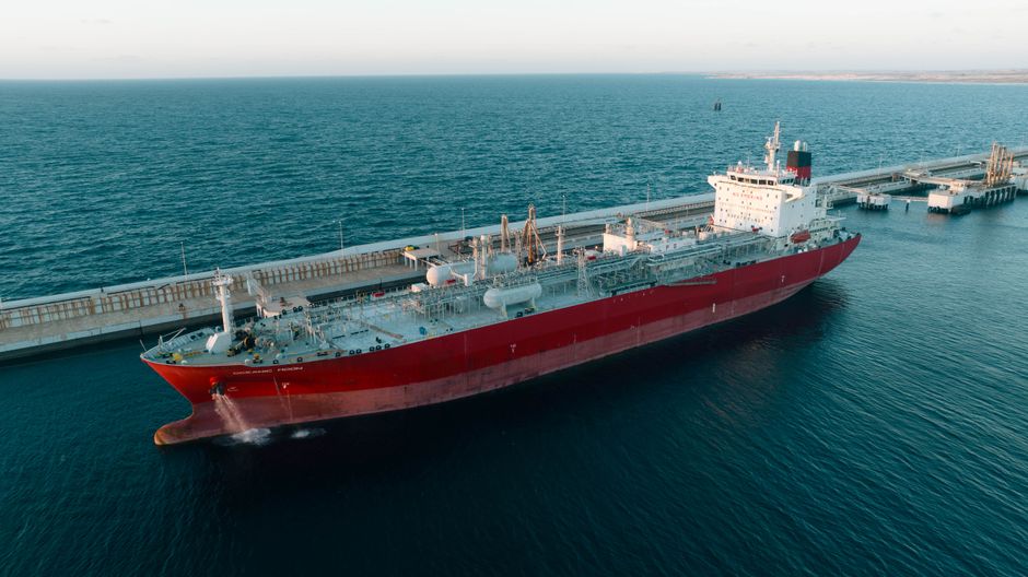 A cargo ship docked at a coastal port, representing maritime logistics at the center of the Hormuz supply risk.